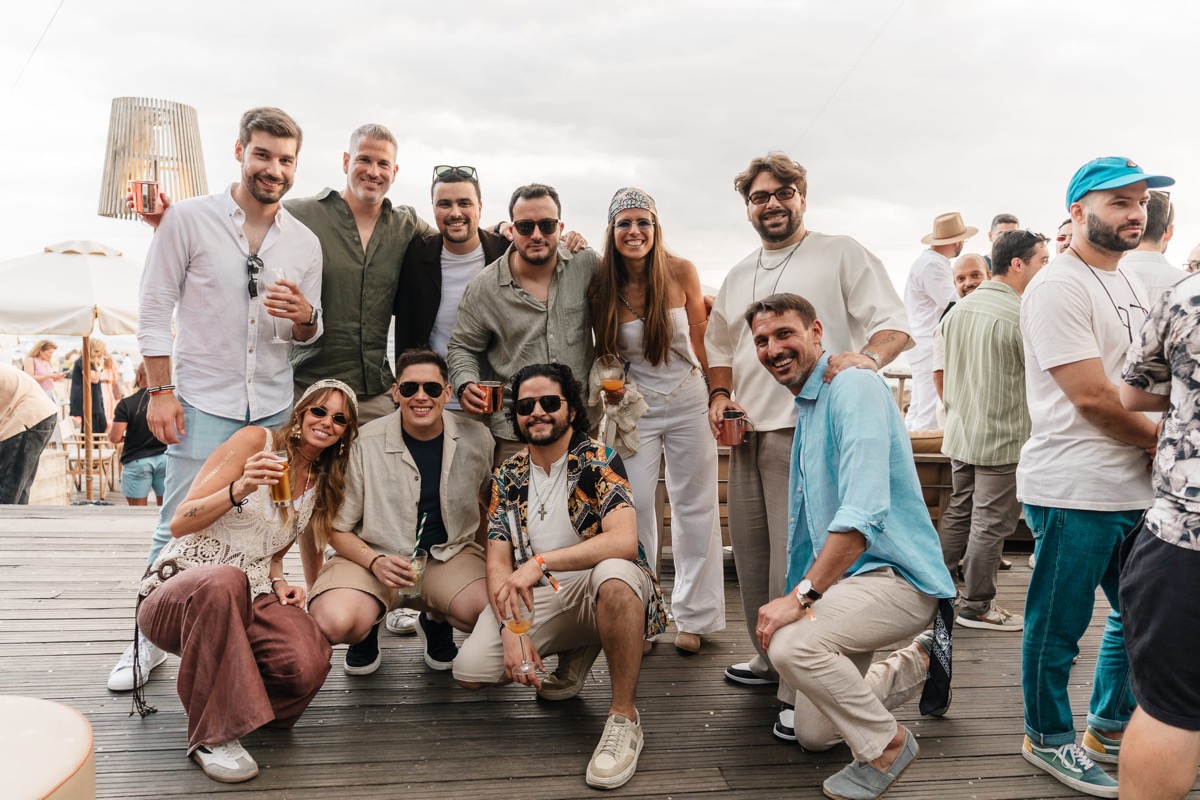 xelerate.tech colleagues posing together with drinks at a company party by the sea